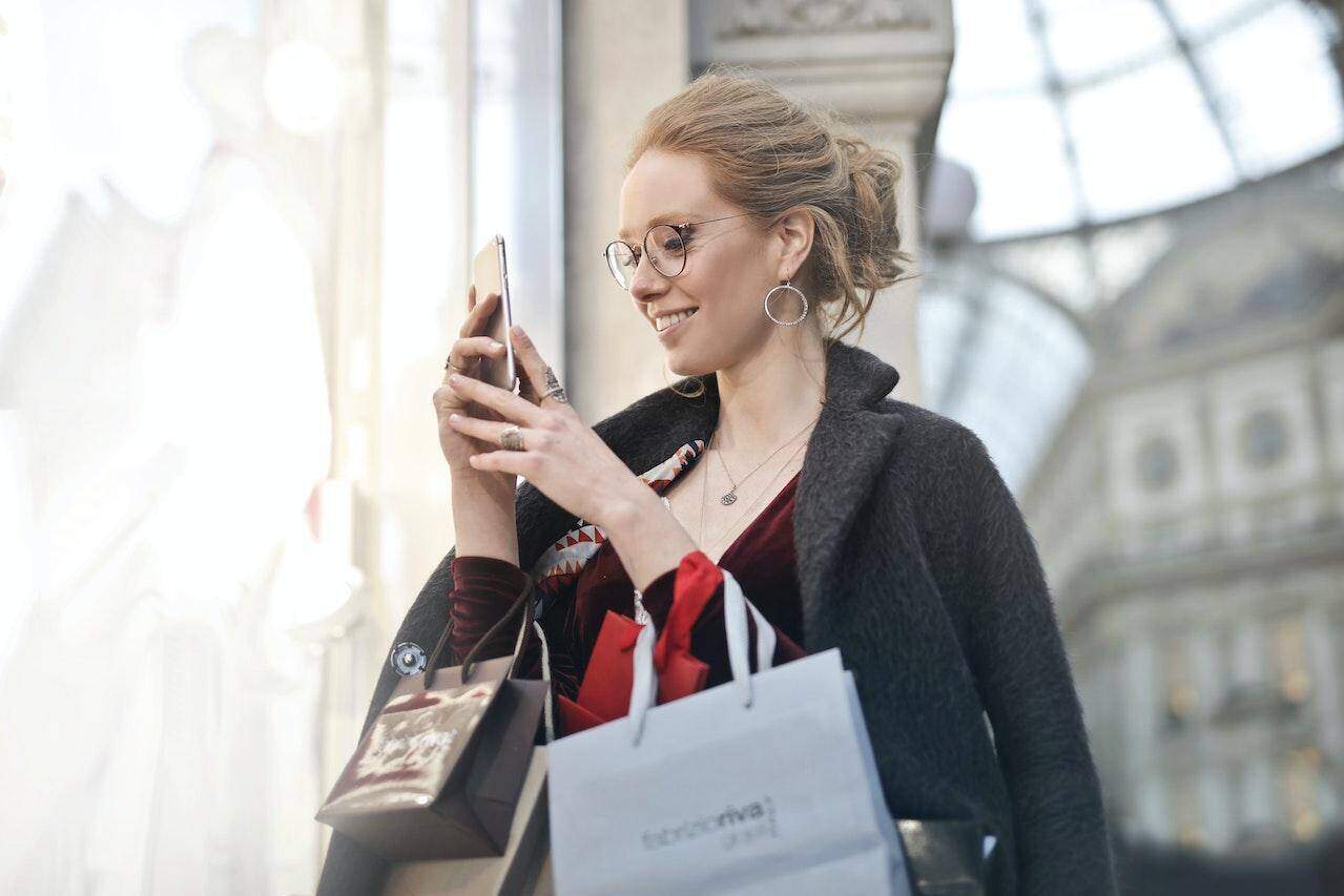 Kobieta sprawdza w telefonie dotykowym swoją nagrodę za realizację badania Mystery Shopper